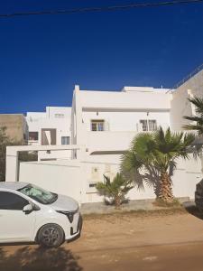 a white car parked in front of a white building at Jasmin Prestige Duplex - Hammamet in Hammamet