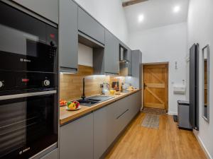 a kitchen with white cabinets and black appliances at The Aran - Uk51067 in Frongoch +7 photos