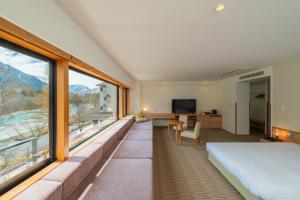 a bedroom with a bed and large windows at Kamikochi Lemeiesta Hotel in Matsumoto