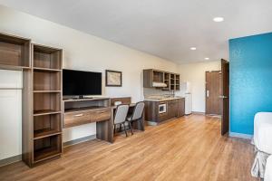 a room with a bed and a desk with a television at WoodSpring Suites Naples East in Naples