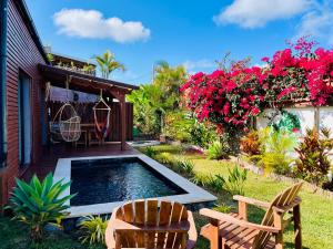 a backyard with a pool and two chairs and flowers at Anaélodge in Le Tampon
