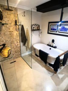 a bathroom with a tub and a glass shower at Boutique Inn - Quintessence in Gordonʼs Bay