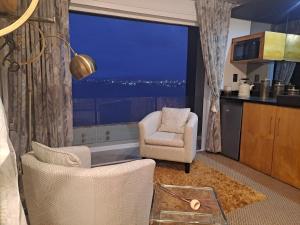 a living room with two chairs and a large window at Boutique Inn - Quintessence in Gordonʼs Bay