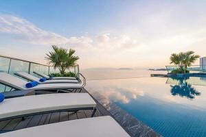 a swimming pool with lounge chairs and the ocean at Boton Blue Hotel & Spa in Nha Trang