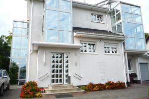 a white house with glass windows and flowers at Appartementhaus Mila in Kolobrzeg in Kołobrzeg