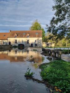 a building with a river in front of it at Zen suite Moulin de Vilaine in Châteauroux