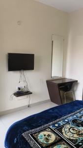 a bedroom with a bed and a desk and a television at Hotel Surya in Datia