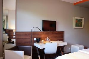 a room with a table and a tv on a wall at Hotel Saint-Hubert in Hambach