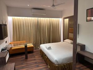 a bedroom with a bed and a couch and a television at Windsor House in Secunderabad