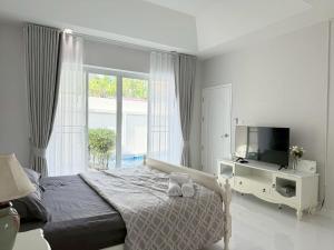 a bedroom with a bed and a tv and a window at Buddy pool villa in Nong Prue