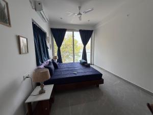 a bedroom with a bed with blue sheets and a window at Riverfront Grand By GikiJoy in Siolim