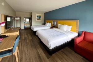 a bedroom with two beds and a desk and a red chair at Park Inn by Radisson, Weldon - Roanoke Rapids in Weldon +5 photos