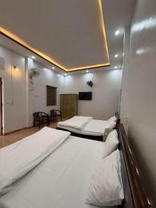 a room with two beds and a tv on the wall at Phong Khánh Hostel in Than Uyên