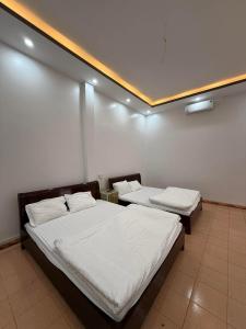 two beds in a room with white walls at Phong Khánh Hostel in Than Uyên