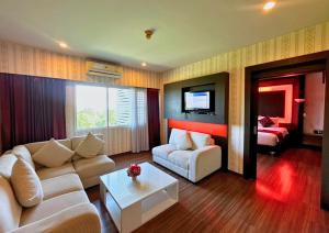 a living room with a couch and a tv at Akelada Hotel in Nang Rong