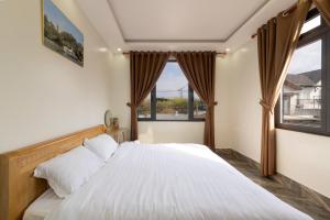 a bedroom with a large white bed with windows at Healling home 1 in Da Thien