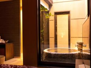 ein Badezimmer mit einer großen Badewanne in einem Zimmer in der Unterkunft 大分温泉 Business Resort Sourin in Ōita