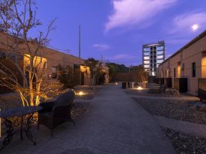 ein Gehweg mit Stühlen und Beleuchtung neben einem Gebäude in der Unterkunft 大分温泉 Business Resort Sourin in Ōita
