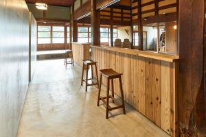 a bar with stools in a room with wooden walls at kitanUOZU in Uozu