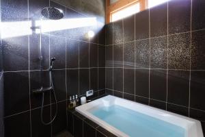 a bathroom with a tub and a shower at kitanUOZU in Uozu