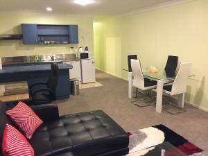 a living room with a table and chairs and a kitchen at DatePalm CBD & Central Akl in Auckland