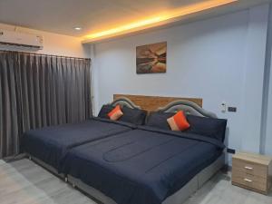 a bedroom with a large blue bed with orange pillows at Triple J Hometel in Bang Tao Beach