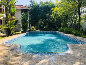 a swimming pool with blue water in a yard at Thambapanni Villa in Unawatuna