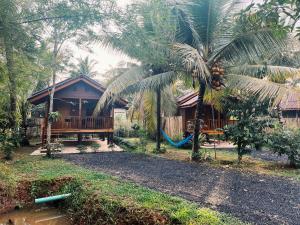 a house with a palm tree in front of it at Decoco Canal-side Homestay in Ban Khlong Duang