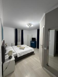 a white bedroom with a bed and a mirror at White Wood Chalet in Buşteni