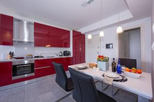 kuchnia z czerwonymi szafkami i stołem z krzesłami w obiekcie Casa Laura Apt 3 w mieście Menaggio