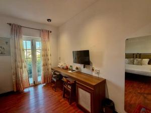 a room with a desk with a television and a bed at Lynk Stay Hoian in Hoi An