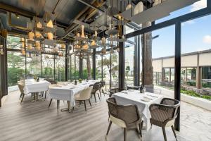 a restaurant with white tables and chairs and large windows at Arbor Hotel - Signature Collection in Istanbul