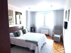 a bedroom with a large bed and a chair at A CALZADA in Cambados