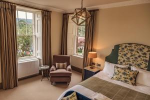 a bedroom with a bed and a chair and windows at The Residence by Atholl Arms in Dunkeld