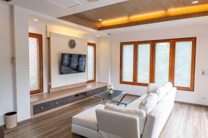 a living room with a white couch and a tv at Premium Villa Baan Kinlom Chomlay in Hua Hin