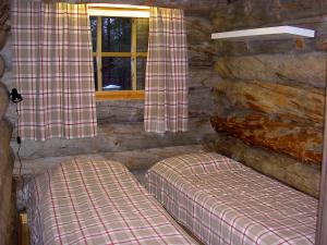 a log cabin bedroom with two beds and a window at Northern Lights in Levi