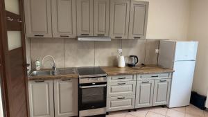 a kitchen with white cabinets and a white refrigerator at Apartament 10 Słoneczna in Ełk
