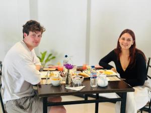 a man and woman sitting at a table with food at H M C Leisure Villa Devinuwara in Dondra North