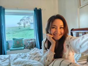 a woman laying in bed talking on a cell phone at Fernbrook Lodge in Dorrigo