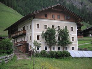 a large white house in a field next to a mountain at Ferienwohnung Innerlipper in Innervillgraten