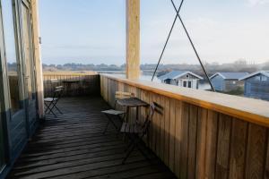 a balcony with chairs and tables and a view of the water at Brouwersdam Stay in Ouddorp +38 photos