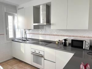 a white kitchen with white cabinets and a microwave at A CALZADA in Cambados