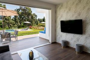 a living room with a flat screen tv on a wall at Sani Beverly Hills Luxury Villas in Sani Beach