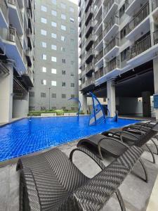 an empty swimming pool in a building with chairs at Chic Urban Escape at S Residence Tower 3 in Manila