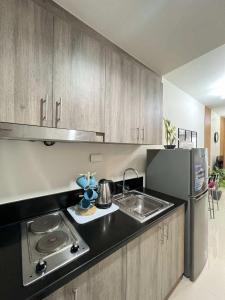 a kitchen with a stove and a sink and a refrigerator at Chic Urban Escape at S Residence Tower 3 in Manila