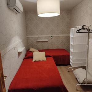 two beds in a small room with a red blanket at CENTRO HISTORICO in Manzanares