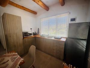 a kitchen with a refrigerator and a sink and a window at Intimate Studio for Two at Hebron Estate in Piketberg