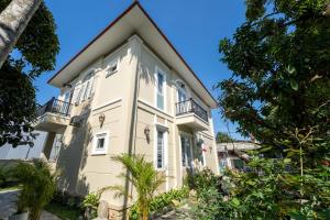 a large white house with balconies and trees at Kim Luông Homestay in Thôn An Hòa