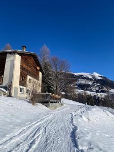 a house on a snow covered hill next to a house at Moomooland in Bergün