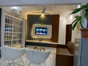 a living room with two white chairs and a tv at 2 chambres salon au calme in Porto-Novo +11 photos